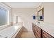 Bright bathroom with a large window, soaking tub, and wooden cabinets with a double sink at 28 Lee Woods Dr, Clayton, NC 27520
