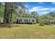 Quaint home features lush green lawn with lots of mature trees surrounding the house at 308 Plaza Dr, Garner, NC 27529