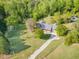 Aerial view of a home nestled among trees with a long driveway and surrounding greenery and a small outbuilding at 317 William Dr, Benson, NC 27504