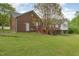 Backyard view showcasing a brick house with a deck, steps, and a spacious, well-maintained lawn at 317 William Dr, Benson, NC 27504