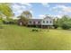 Large backyard featuring a brick home with an elevated wooden deck, surrounded by lush green grass and mature trees at 317 William Dr, Benson, NC 27504