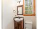Cozy half bath with a wooden vanity, framed mirror, towel rack, and a window offering natural light at 317 William Dr, Benson, NC 27504