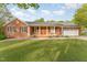 Charming brick home with a covered front porch, black shutters, and a well-maintained lawn and garage at 317 William Dr, Benson, NC 27504