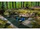 Backyard with serene pond featuring a stone bench surrounded by lush landscaping at 3719 W Cornwallis Rd, Durham, NC 27705