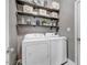 Functional laundry room with washer, dryer, overhead shelves, and plenty of storage space at 387 Windgate Dr, Clayton, NC 27527