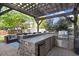 Outdoor kitchen with built-in grill, beverage cooler, sink, bar seating and wood pergola at 387 Windgate Dr, Clayton, NC 27527