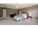 Well lit bedroom featuring carpeted floor, tiered chandelier, a gray accent wall, and a bed with bench at 3920 Bentley Brook Dr, Raleigh, NC 27612