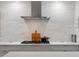 Close up of kitchen features marble back splash, stainless steel range hood, and gas cooktop on white counter at 3920 Bentley Brook Dr, Raleigh, NC 27612