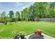 Lush backyard with green grass, mature trees, a wooden fence, and a patio with potted plants at 416 Glenview Ln, Durham, NC 27703