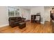 Living room showcasing the hardwood floors, cozy leather sofa, and natural light from the windows at 431 Waddill St, Henderson, NC 27536