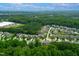 Expansive aerial view of a neighborhood surrounded by lush greenery and a serene pond at 521 Wildwood Farm Way, Holly Springs, NC 27540