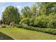 Green backyard featuring a lush lawn, garden, and mature trees with private setting at 521 Wildwood Farm Way, Holly Springs, NC 27540