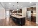 Modern kitchen with an island and seating, stainless steel appliances, dark cabinets, and hardwood flooring at 521 Wildwood Farm Way, Holly Springs, NC 27540