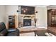 Living room with a stone fireplace, built-in shelving, and a large television at 521 Wildwood Farm Way, Holly Springs, NC 27540
