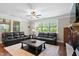 Cozy living room with dark leather sofas, a coffee table, and windows that let in natural light at 521 Wildwood Farm Way, Holly Springs, NC 27540