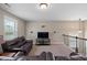Spacious loft area with plush brown couches, large window, media center, and view of decorative staircase at 521 Wildwood Farm Way, Holly Springs, NC 27540