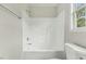 Bright white bathroom featuring a shower-tub combination and toilet under a window at 5505 Armada Dr, Raleigh, NC 27610