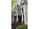 Charming porch entrance with stone columns, a welcome flag, and vibrant landscaping at 572 W Walker Woods Ln, Clayton, NC 27527