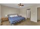 Neutral bedroom featuring tan walls, carpet, ceiling fan, and adjacent bathroom and hallway at 5900 Shady Grove Cir, Raleigh, NC 27609