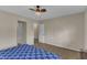 Bedroom with a blue patterned bedspread, neutral walls, a ceiling fan and two doorways at 5900 Shady Grove Cir, Raleigh, NC 27609
