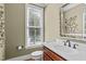 Powder room featuring a vanity with white countertop, decorative mirror, and natural light at 629 Peach Orchard Pl, Cary, NC 27519
