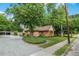 Charming brick home showcasing mature trees, a green lawn, and a gravel driveway at 704 W Front St, Burlington, NC 27215
