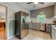 A kitchen is shown with gray cabinets, stainless steel refrigerator, and tiled floors at 704 W Front St, Burlington, NC 27215
