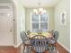 Bright dining area featuring modern chandelier, wood table with six chairs, and large sunny windows at 7328 Caversham Way, Raleigh, NC 27617