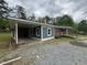 Angle view of a brick home showcasing a covered carport, and gravel driveway at 8535 Us-301 S Hwy, Four Oaks, NC 27524