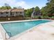 A fenced community swimming pool with a ladder, grass area, and surrounding townhomes for summer fun at 1020 Randolph Ct, Cary, NC 27511