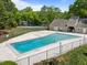 A community swimming pool surrounded by a fence, grass, and trees provides a refreshing amenity at 1020 Randolph Ct, Cary, NC 27511