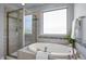 Bright bathroom featuring a soaking tub, walk-in shower, tile accents, and natural light from a large window at 1033 Laredo Ln, Durham, NC 27703