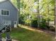 A serene backyard featuring lush greenery, mature trees, and a charming cottage-style home in the background at 105 Hein Dr, Clayton, NC 27527