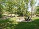 Backyard with a stone firepit and chairs surrounded by a well-maintained lawn and mature trees at 105 Hein Dr, Clayton, NC 27527
