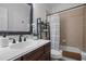 Bathroom featuring a wood vanity, framed mirror, and a shower-tub combo with white and beige tile at 107 Deer St, Carrboro, NC 27510