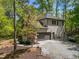 View of home featuring an attached two-car garage with gravel driveway surrounded by mature trees in a neighborhood setting at 107 Deer St, Carrboro, NC 27510