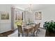 Bright dining room features natural light, a modern chandelier, table set for meal, and backyard views at 10805 The Olde Pl, Raleigh, NC 27614