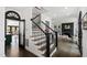 Elegant foyer featuring hardwood floors, staircase with black railing, and an arched doorway leading to the kitchen at 10805 The Olde Pl, Raleigh, NC 27614