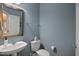 Cozy half bath with a pedestal sink, framed mirror and blue accent wall at 126 W Savannah Ridge Rd, Holly Springs, NC 27540