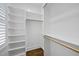 Spacious walk-in closet with white shelving, wooden rods, and classic dark hardwood flooring at 1306 Mordecai Dr, Raleigh, NC 27604