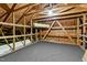Unfinished attic space, featuring exposed wooden beams and gray carpeting, offering potential for customization at 13338 Ashford Park Dr, Raleigh, NC 27613