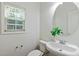 Neutral powder room featuring a pedestal sink, toilet, and leafy green accent at 13338 Ashford Park Dr, Raleigh, NC 27613