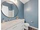 Stylish blue bathroom with a large round mirror, white vanity, and modern fixtures at 1605 Grace Point Rd, Morrisville, NC 27560