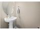 A clean, simple powder room features a pedestal sink, oval mirror, and towel rack at 1605 Grace Point Rd, Morrisville, NC 27560