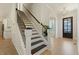 Entryway with staircase featuring dark wood treads and handrail, as well as a modern chandelier at 1724 Deacon Falls Way, Wendell, NC 27591