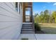 Inviting front entrance with wood-stained stairs, white siding, and a view of the lush lawn and mature trees at 1724 Deacon Falls Way, Wendell, NC 27591