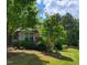 Charming home with lush green lawn, mature trees and bushes, and an American flag displayed on the porch at 2008 Stanwood Dr, Apex, NC 27502