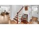 Hallway showcasing beautiful hardwood floors, a staircase with wooden railing, and neutral walls at 2008 Stanwood Dr, Apex, NC 27502