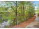 Scenic view of a tranquil pond surrounded by trees and greenery, with a paved path alongside the water at 2008 Stanwood Dr, Apex, NC 27502