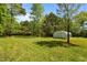 Spacious backyard featuring a storage building, mature trees, and a swing on a well-manicured lawn at 209 Pen Lou Ct, Angier, NC 27501